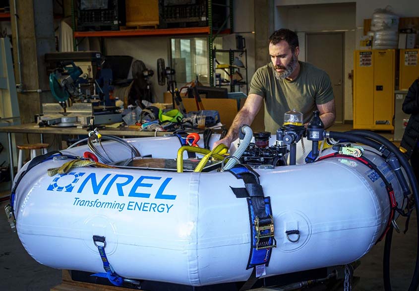 A person adjusts equipment stashed in the middle of an inflated octagonal ring in a lab