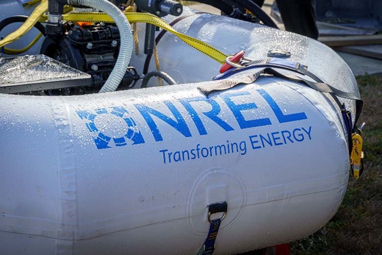The NREL Transforming Energy logo is printed on the side of an inflated tube covered in water droplets