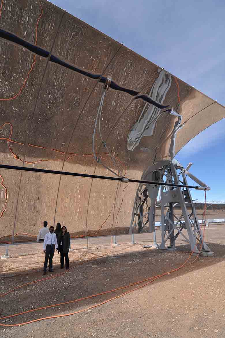 Two people standing in the shade under a huge curved mirror