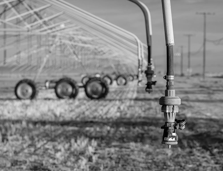 A dry field with a large irrigation system dripping water