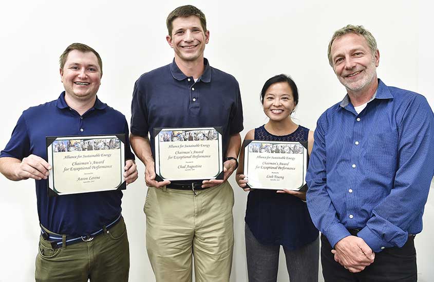 Aaron Levine stands next to Chad Augustine and Linh Truong; all three award winners hold their certificates while Martin Keller stands to the side.