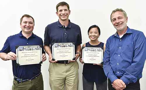 Aaron Levine stands next to Chad Augustine and Linh Truong; all three award winners hold their certificates while Martin Keller stands to the side.