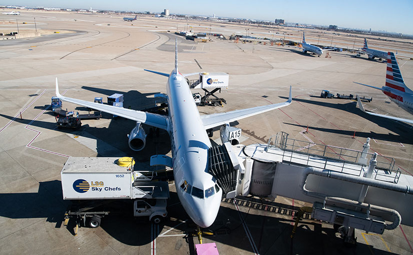 An airplane sits at a gate at a large airport.