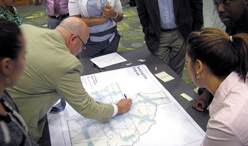 A group of individuals gathered around a table and looking at a map.