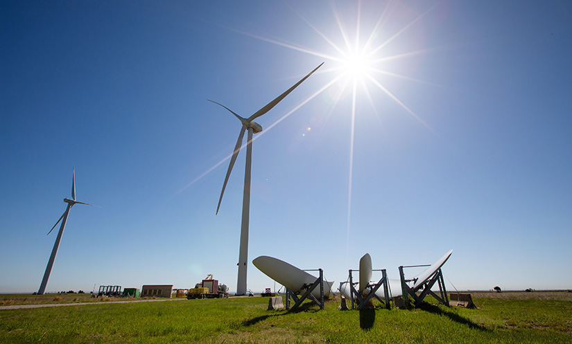 Photo of two wind turbines with blades laying on the ground next to them