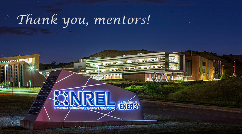 Photo of a campus of buildings at night with a sign in front that reads "NREL"