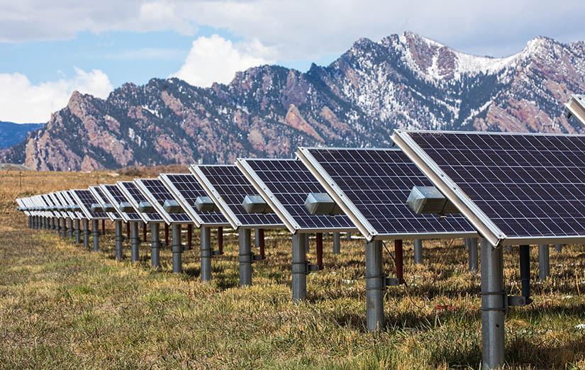 Rows of solar arrays with a view of mountains in the background.