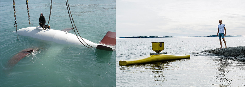 A torpedo-shaped device hanging from chains sits just underwater with a person in SCUBA gear kneeling on top on the left and a device the size of a kayak floats just beyond a rock on which a person stands on the right.