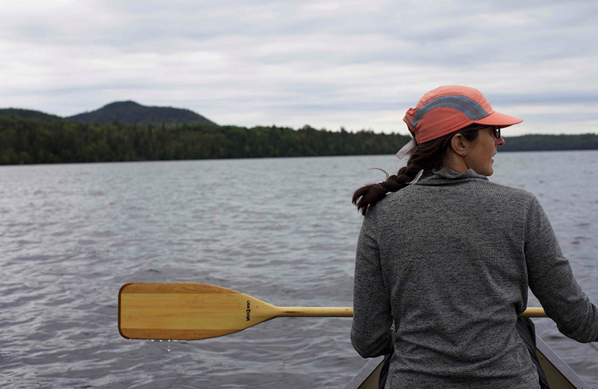 Kerry Strout Grantham sitting in the front of a canoe and looking out across the water with trees and hills in the distance.