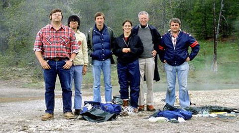 Photo of six people standing outdoors surrounded by trees