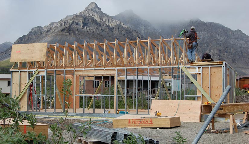 Photograph of building construction with mountains in the background.