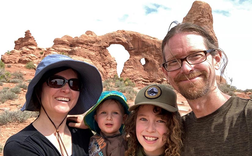 Photo of NREL researcher Anelia Milbrandt, her husband, and two children smiling for a selfie during a hike in Utah. Red rocky landscape is seen in the background.