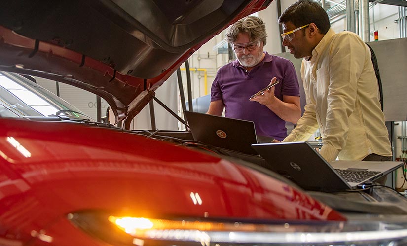 Photo of researchers examining data from an electric vehicle in a laboratory in NREL’s Energy Systems Integration Facility.