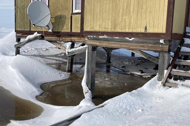 house on wooden stilts surrounded by melting snow