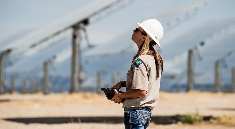 A worker in a hard hat conducting tests at a solar thermal facility.