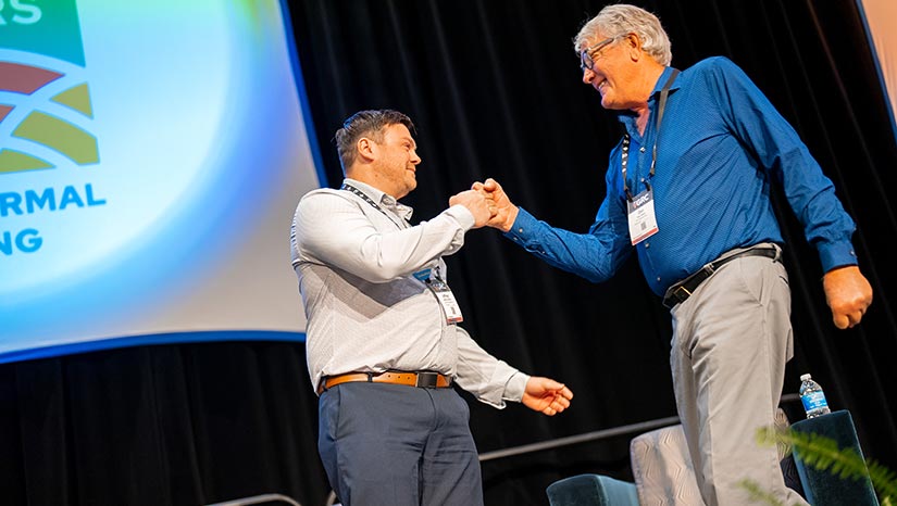 Two people fist-bump on stage.