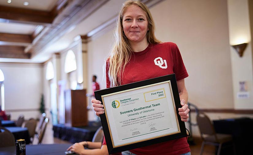 Student holds a framed certificate.