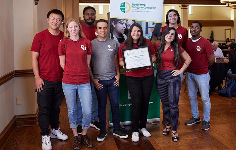 Eight students pose in front of a Geothermal Collegiate Competition banner while holding the winning certificate.