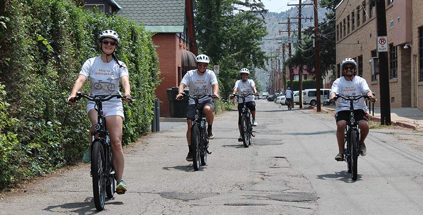 Four people riding bikes in an alley.