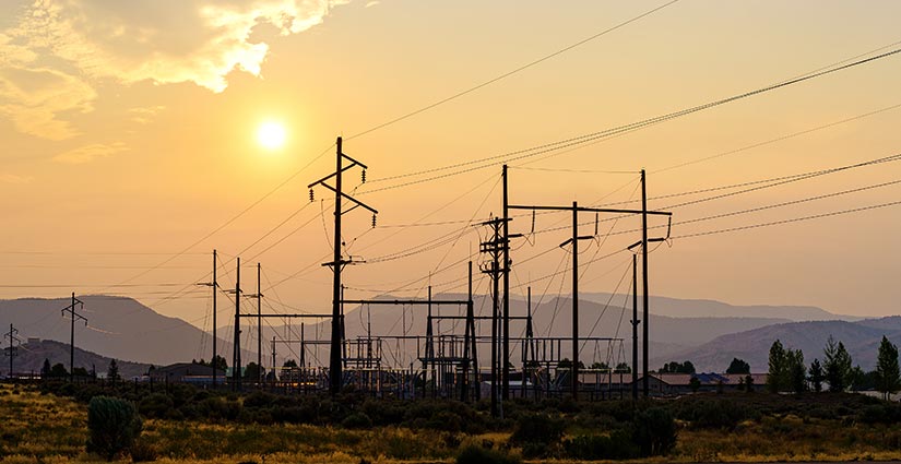 Photo of an electric power plant with a warm sunset in the background due to smoke from a distant forest fire.