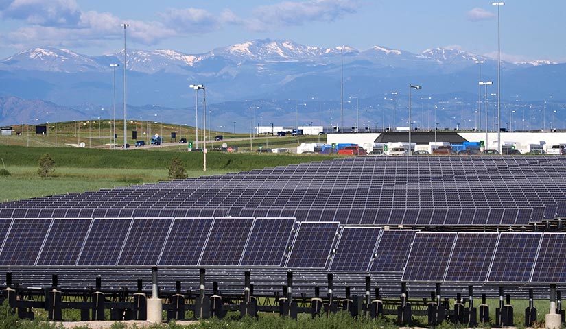 Ground-mounted solar PV array at an airport near mountains.