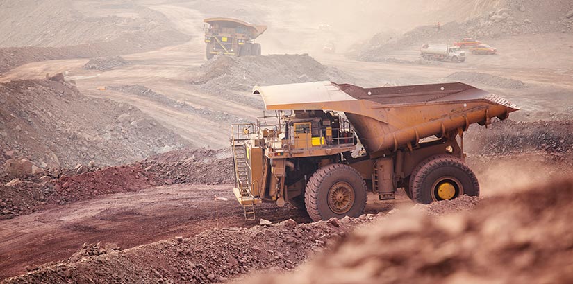 Mining dump truck driving through hills of dirt.