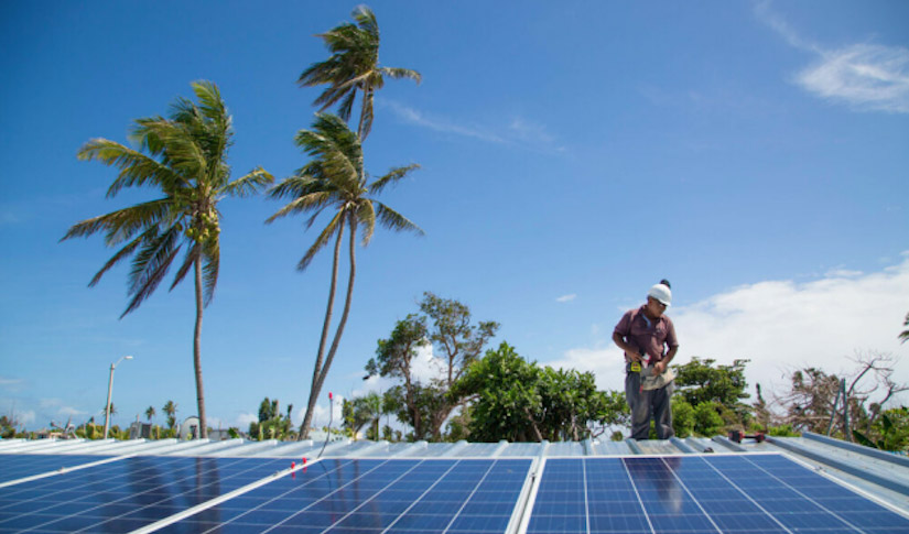 A worker installs solar panels on a roof in Tampa, FL.