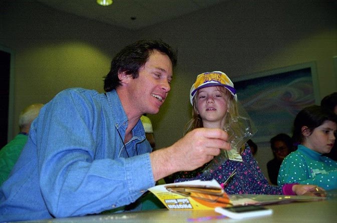 Photo of a man with playing a game with a little girl by his side.