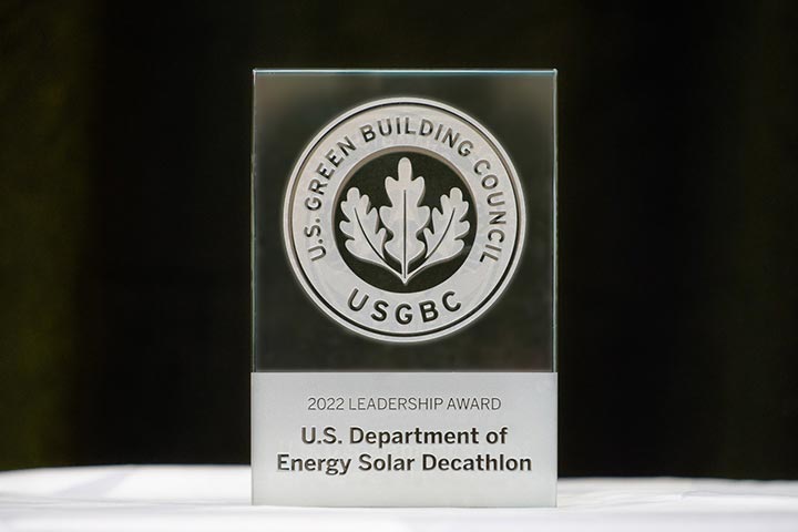 A glass trophy that reads U.S. Green Building Council, 2022 Leadership Award, U.S. Department of Energy Solar Decathlon.