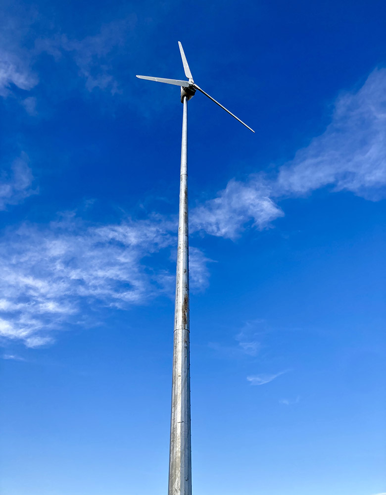 A wind turbine against a blue sky and clouds.