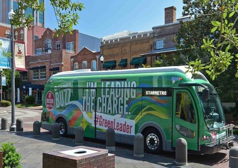 A bus on the street of Tallahassee that says I'm leading the charge and #greenleader