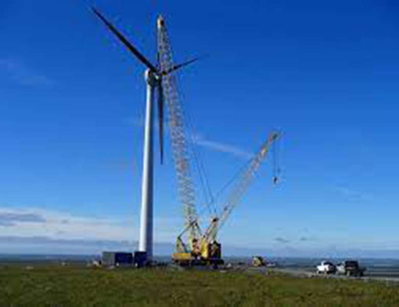 A crane lifting wind turbine blades into place on a tower.