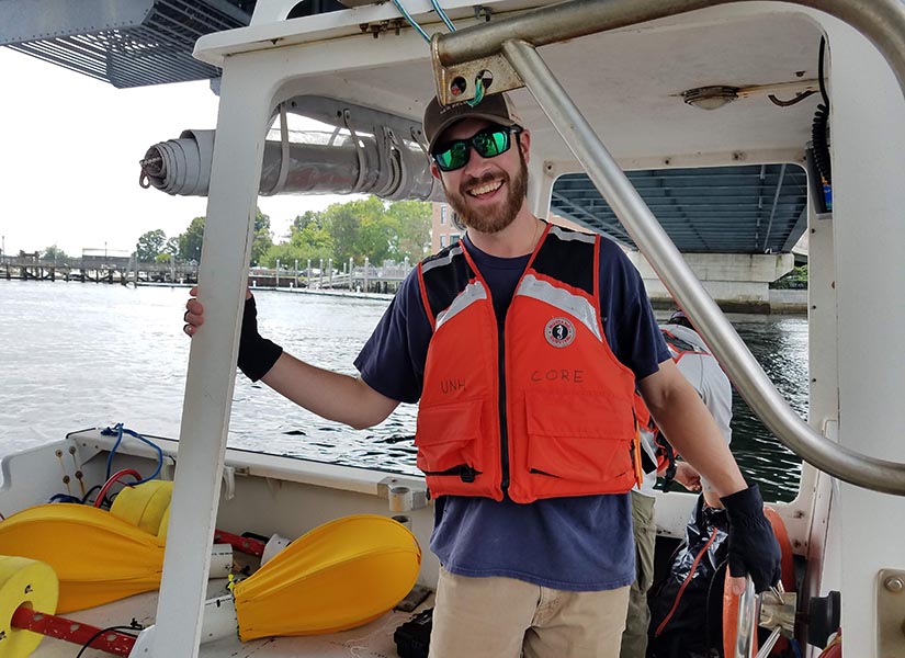 Patrick standing on a boat under a bridge in the middle of a river