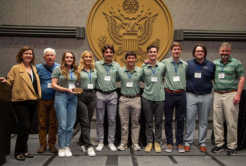 A group of students standing in front of the U.S. seal in matching shirts and name tags.