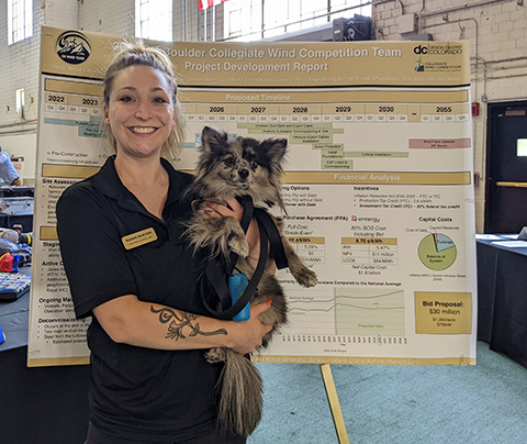 Regan Barton holding a dog and posing in front of a scientific poster.