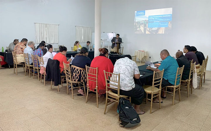 Group of people sit around table watching presentation.