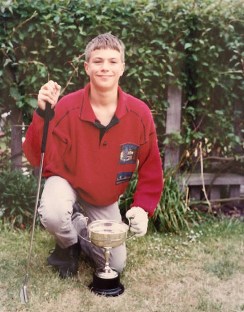 A teenage boy poses with a trophy