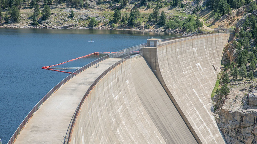 Gross Reservoir Dam, with water and mountains on one side and the steep concrete spillway on the other