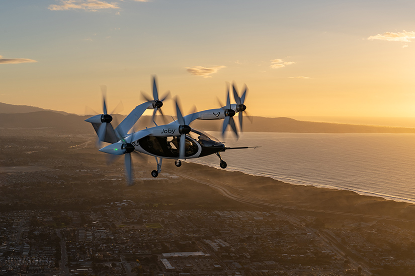 A drone flying over the coast at sunset. 