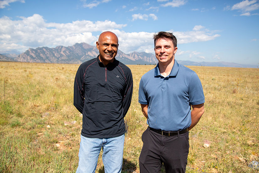 Senu Sirnivas and Stein Housner standing in a field with mountains behind them