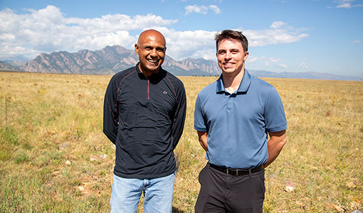 Senu Sirnivas and Stein Housner standing in a field with mountains behind them