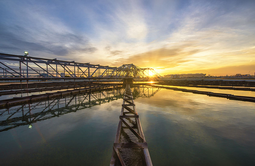 A catwalk extending over a reservoir of water at sunset 