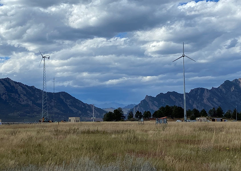 Two wind turbines in a field in front of mountains