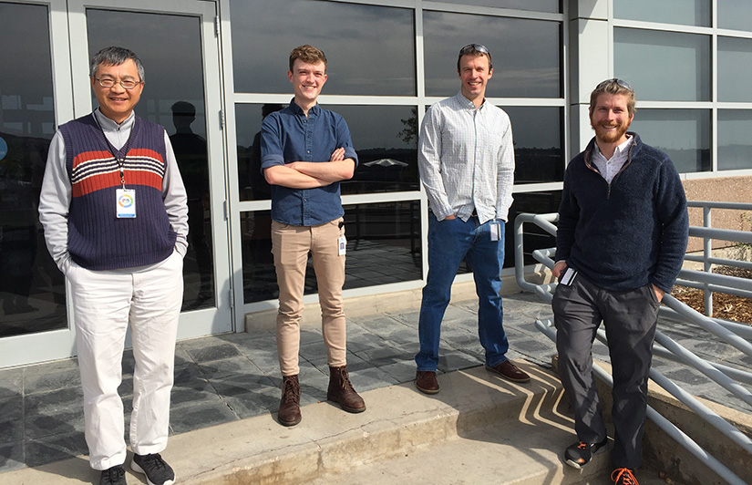 Four people stand on steps outside a building.