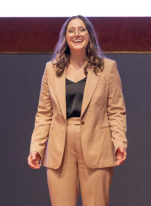 A woman stands on stage and smiles. 