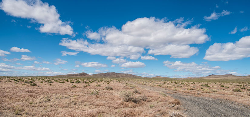 Blue sky with clouds and mountains in the distance.