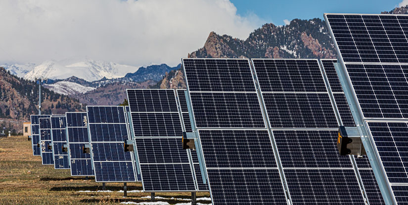 Rows of solar panels with a mountain range in the background.