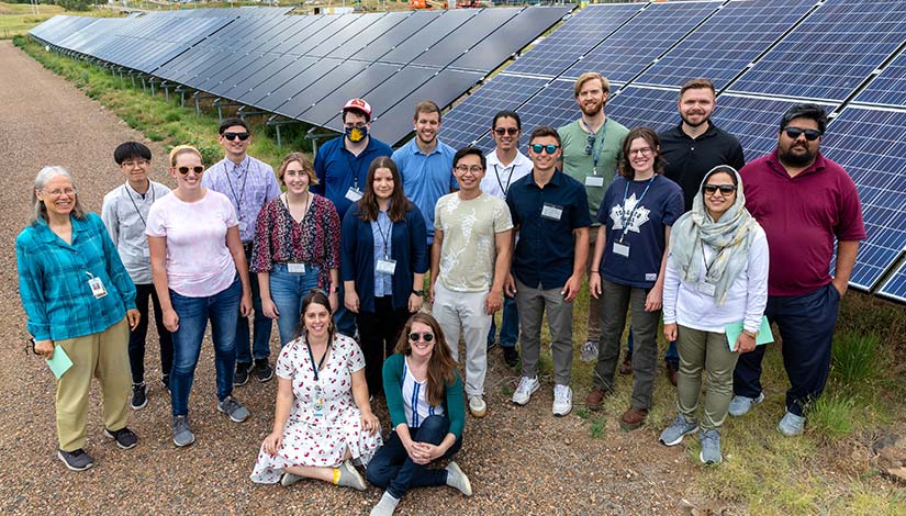 15 HOPE participants and 3 organizers pose for a group photo in front of solar panels.
