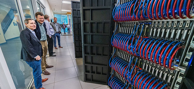 Group of people looking at a computer rack in a data center.