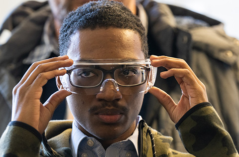 A 2022-2023 JUMP into STEM finalist putting on safety goggles for a tour of NREL.